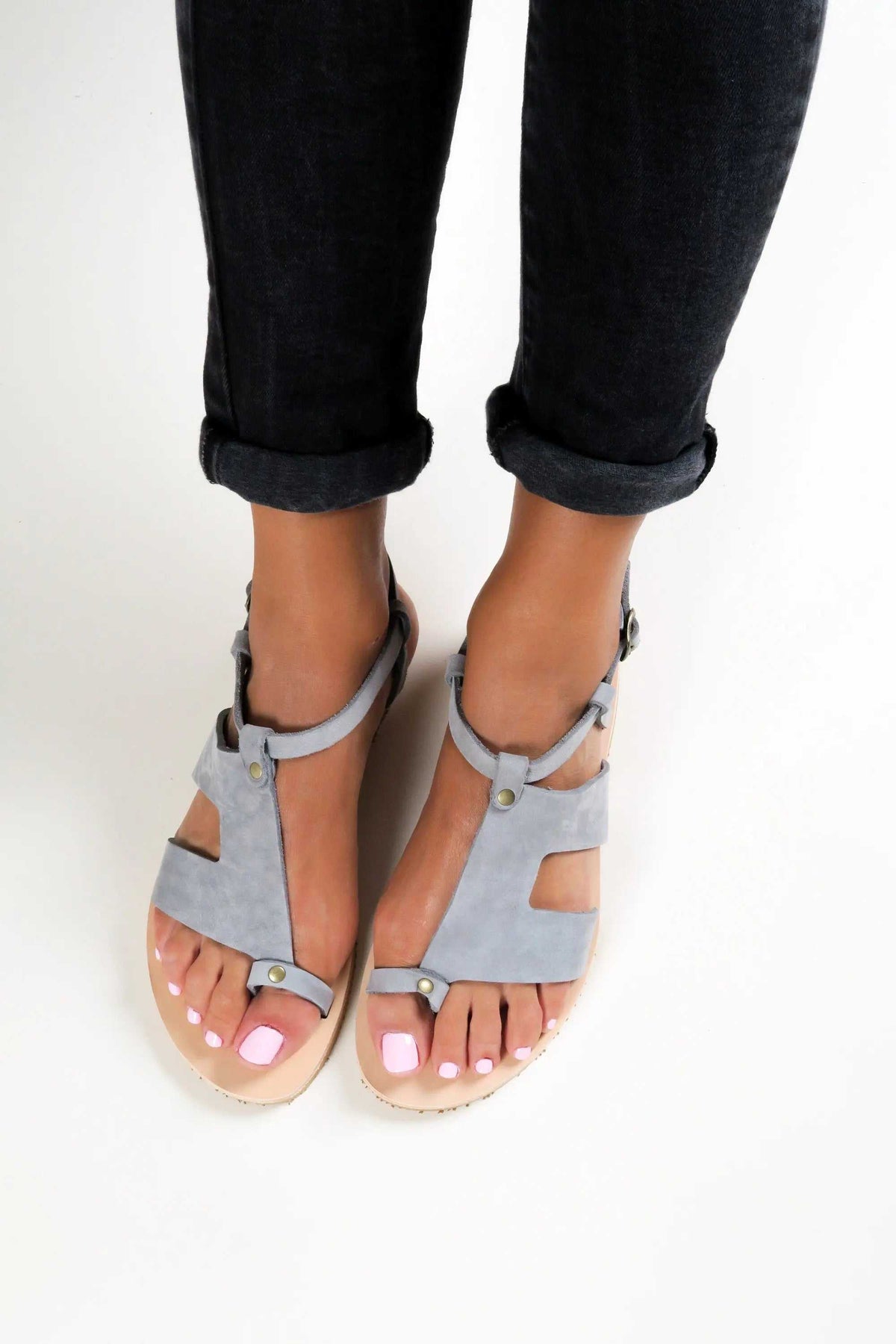 DELOS Handmade Greek Sandals in pale grey suede with tan leather soles, featuring strappy gladiator-style bands and buckles