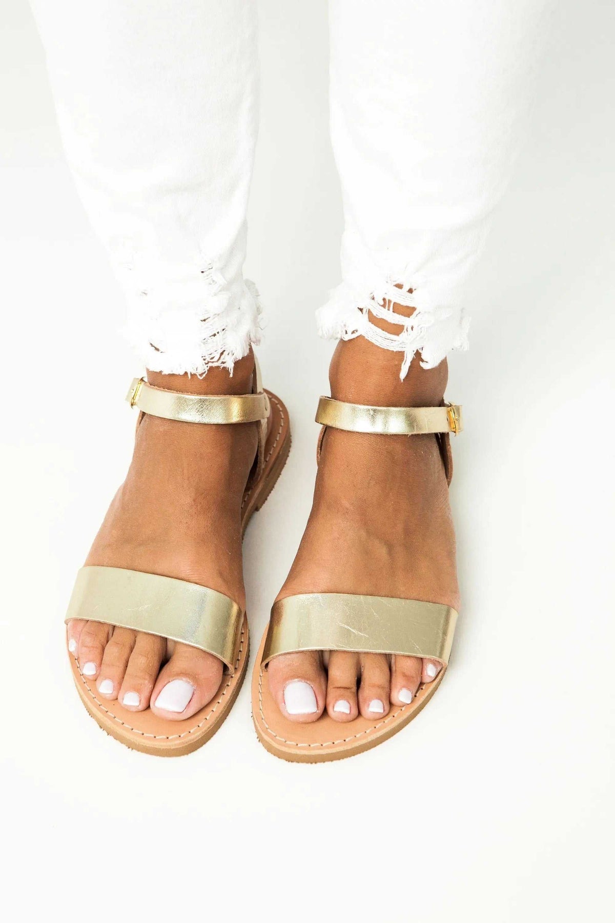 ELOUNDA Handmade Greek Sandals in metallic gold leather, with wide toe straps, slim ankle straps and tan soles