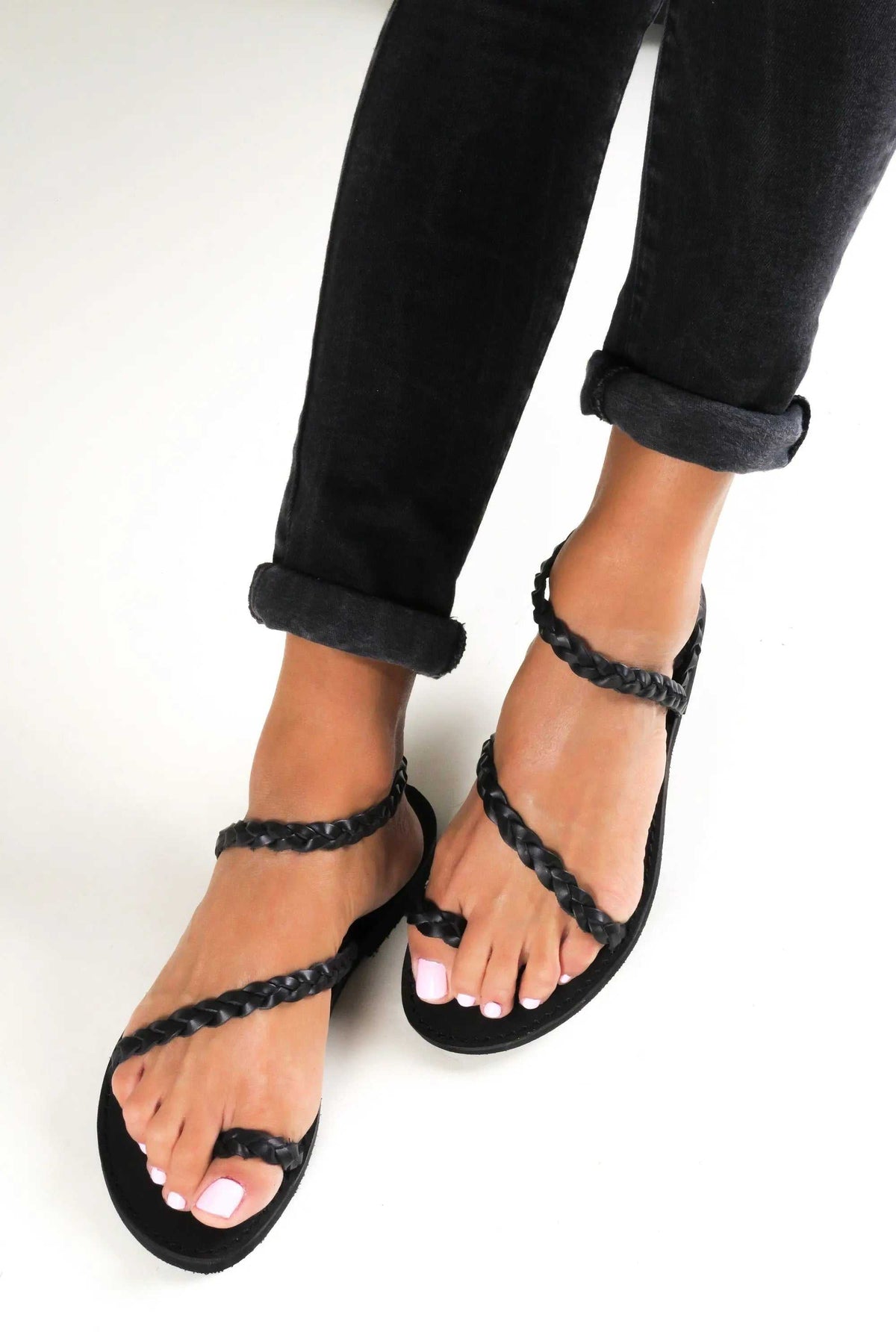 IRO Handmade Greek Sandals with black braided leather straps, open toes and flat soles in a minimalist design