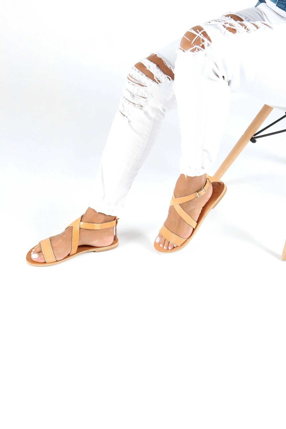 MYRTO Handmade Greek Sandals in natural tan leather with flat soles and crisscross straps secured by ankle buckles