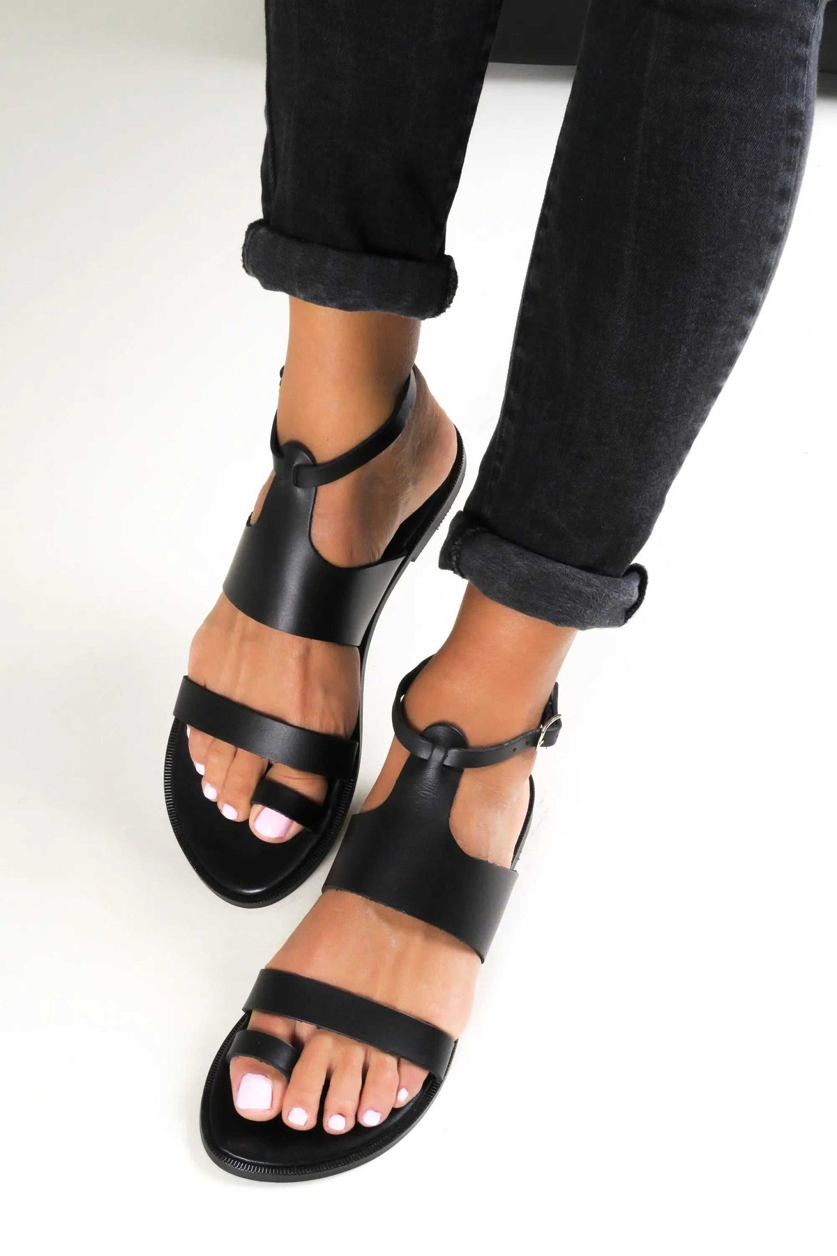 NIKEA Handmade Greek Sandals in black leather with wide straps, open toes and an ankle buckle closure