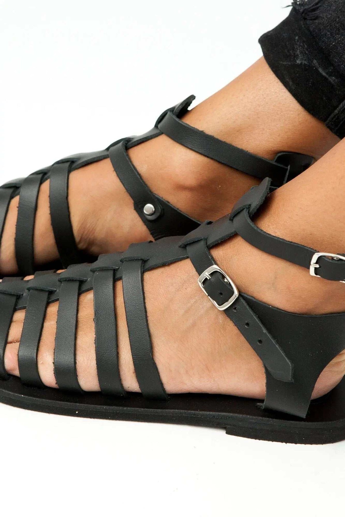 OLYMPE Handmade Greek Sandals in black leather, featuring multiple gladiator straps, silver buckles and a flat sole