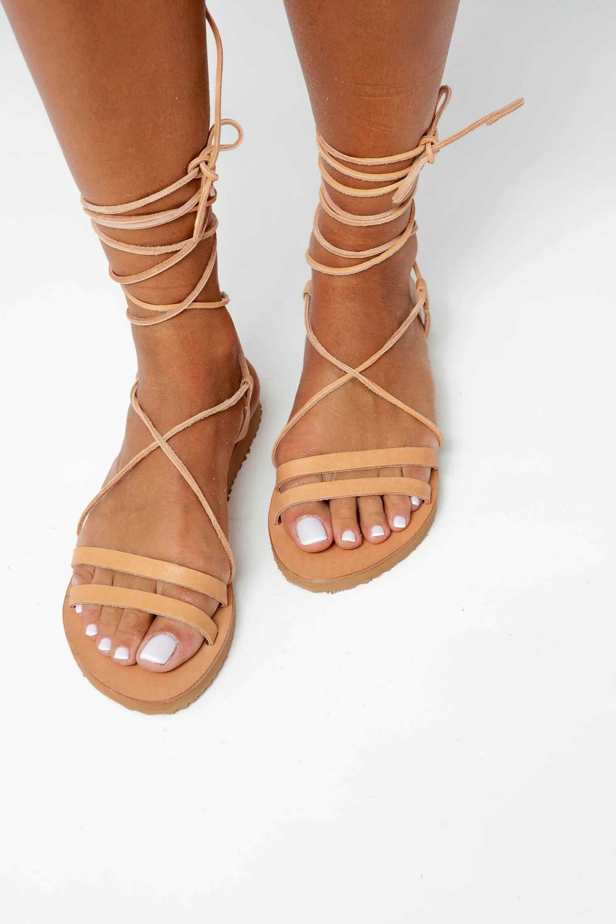 PAXOS Handmade Greek Sandals in natural tan leather, with open toes, flat soles and long wraparound ankle laces.