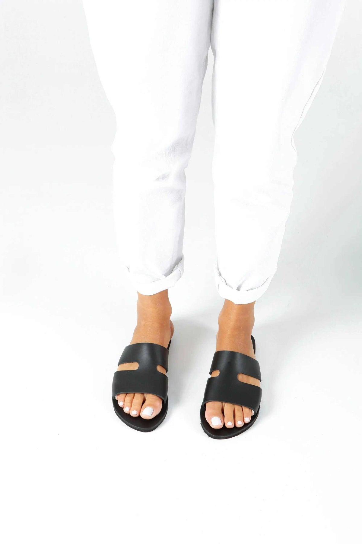 VOTSALO Handmade Greek Sandals, black leather flat sandals with wide straps and open toes, featuring small gold-tone studs.