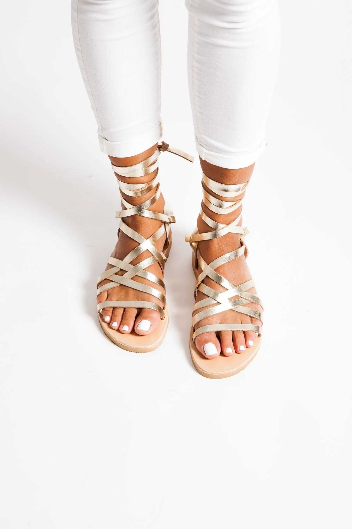 YPSI Handmade Greek Sandals in metallic gold leather with multiple crisscross straps, ankle ties, and flat soles