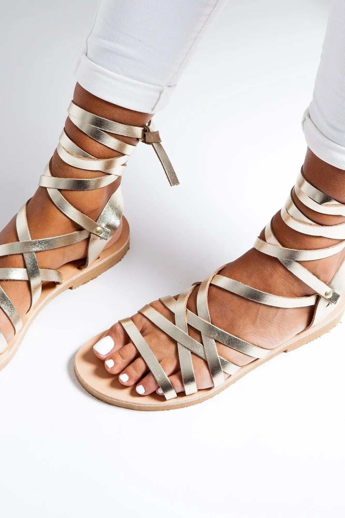 YPSI Handmade Greek Sandals in metallic gold leather with thin crisscrossing straps, ankle ties and a flat sole