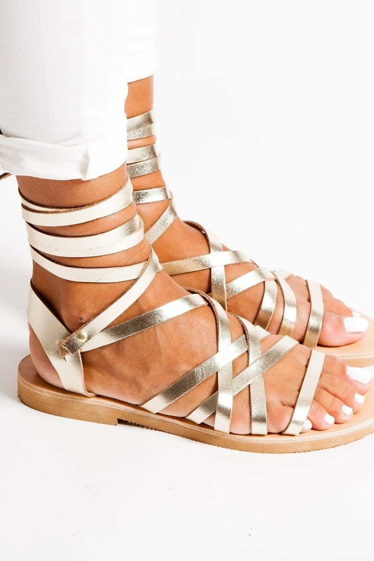 YPSI Handmade Greek Sandals in metallic gold leather with multiple gladiator straps and a flat tan sole