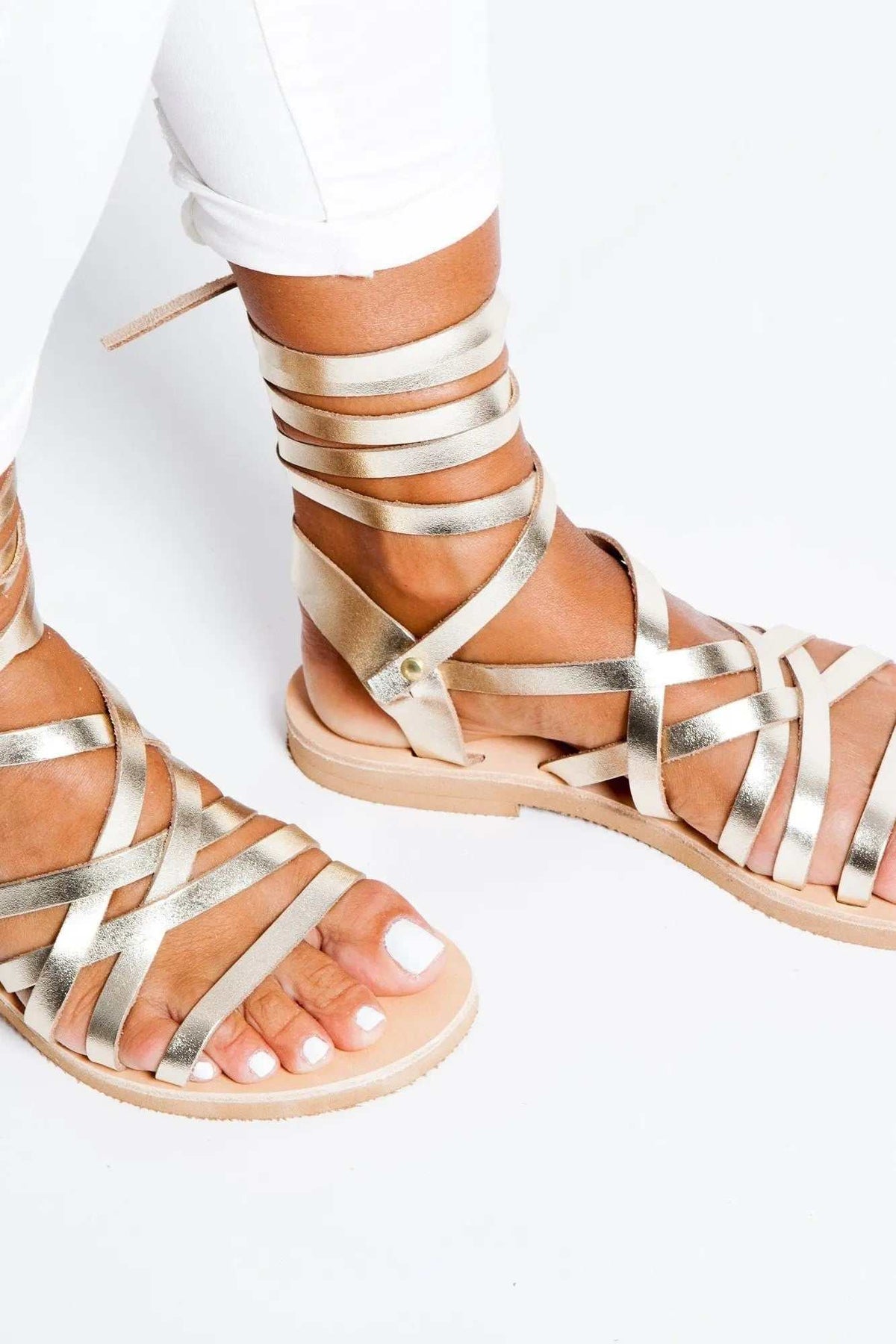YPSI Handmade Greek Sandals in metallic gold leather, with multiple wraparound straps and a flat sole