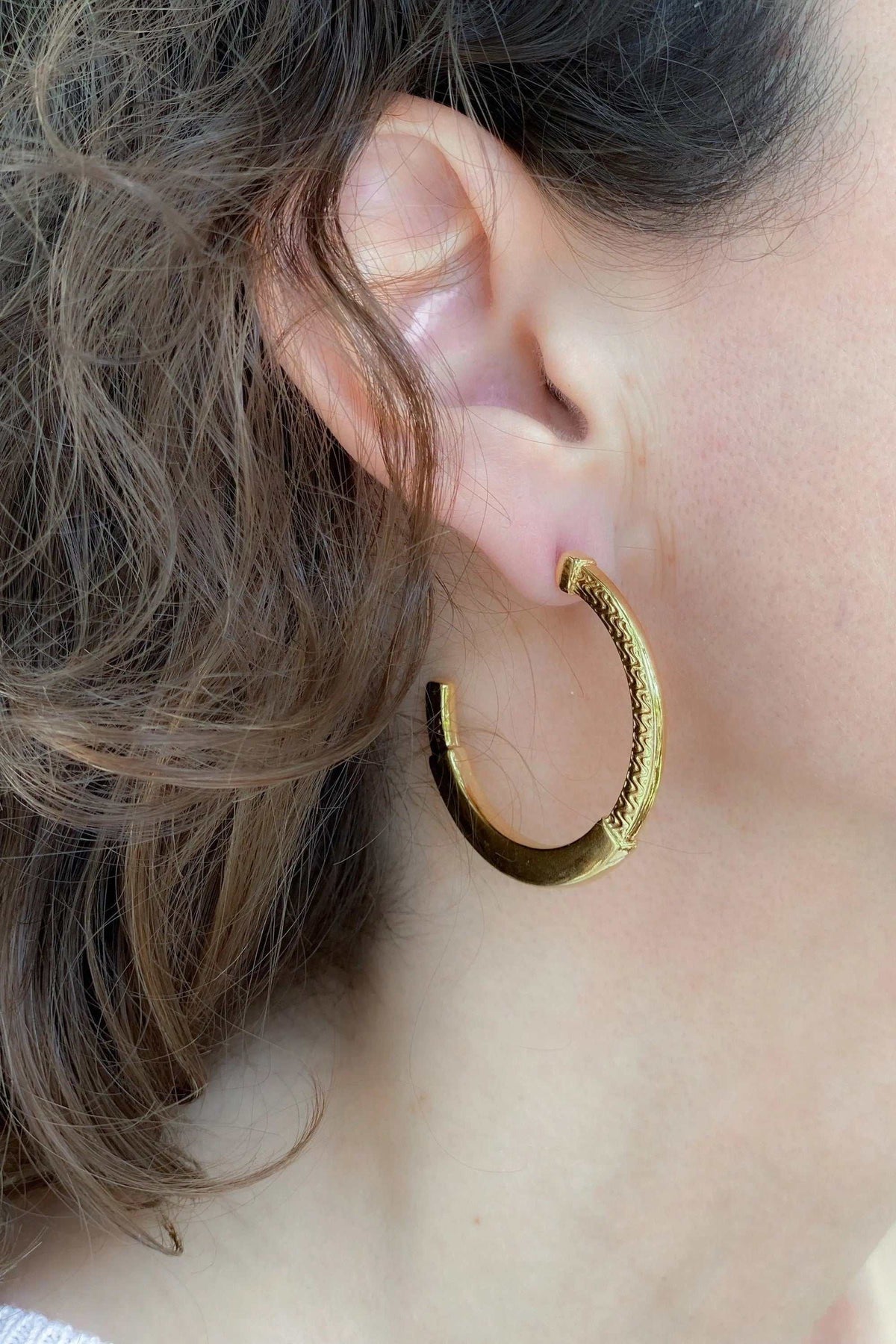 24 k gold filled hoops in gold-tone metal with an engraved tribal pattern and a wide, rounded shape