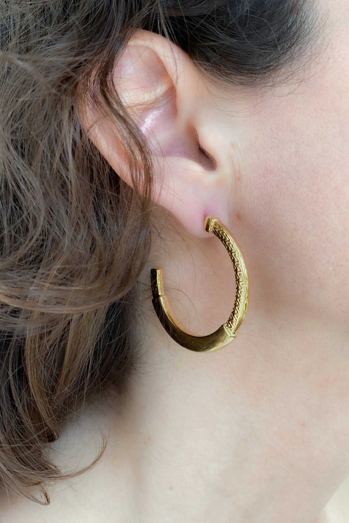 24 k gold filled hoops in a polished gold-tone finish, featuring a wide curved shape and textured tribal pattern