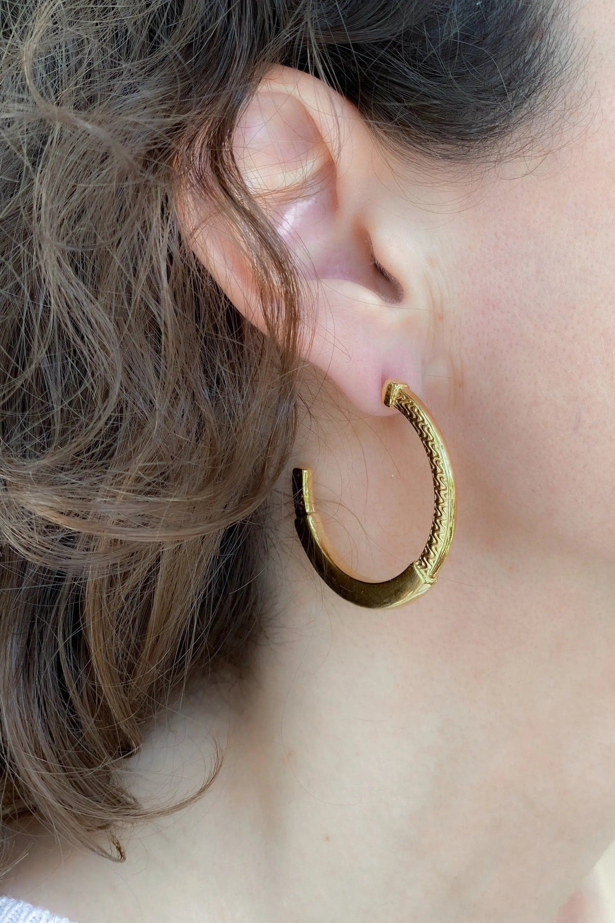 24 k gold filled hoops in polished gold tone with textured tribal pattern and hinged hoop closure