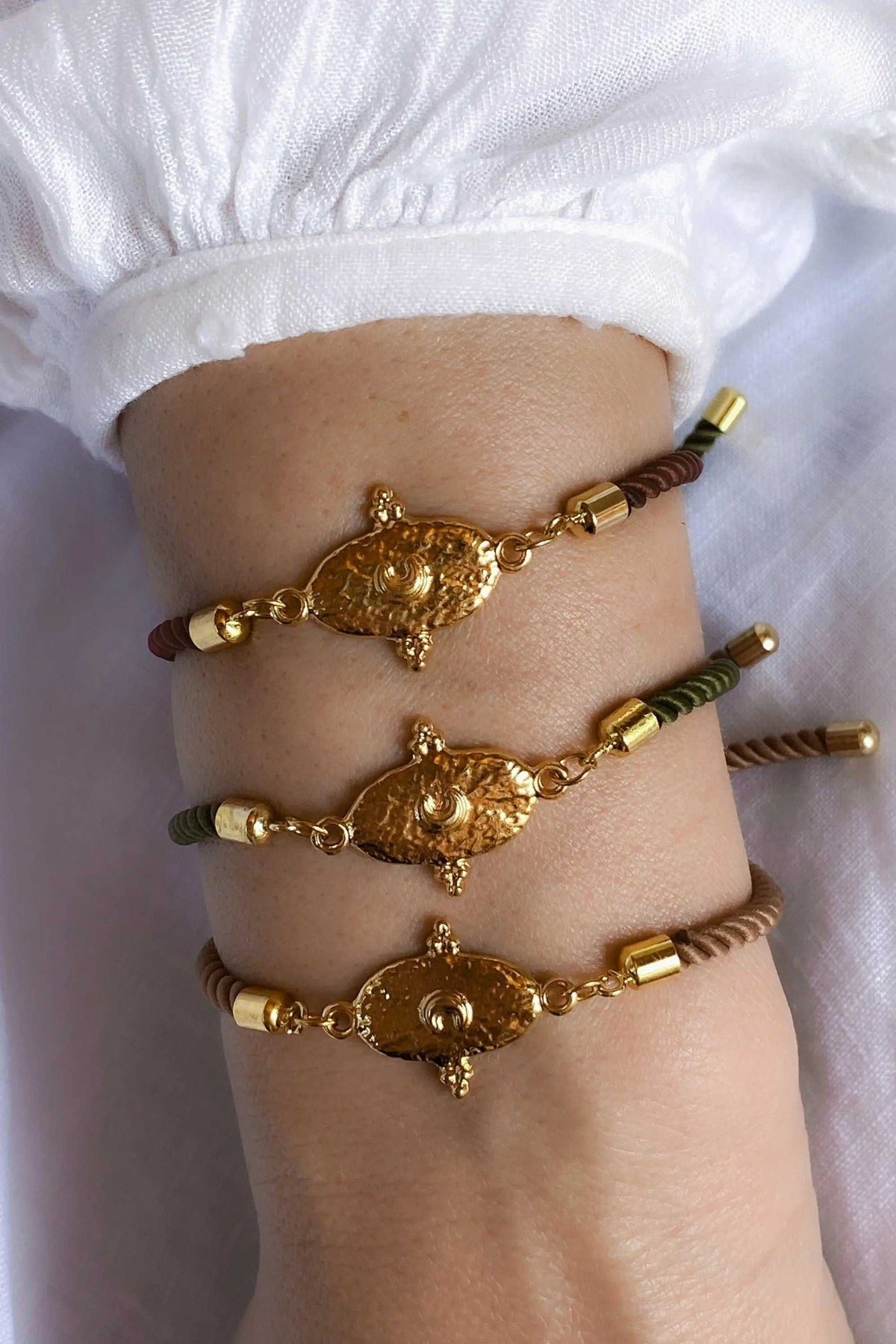 Adjustable rope Bracelet with brown, olive green and tan cords, gold-tone cylindrical beads and ornate tribal charms