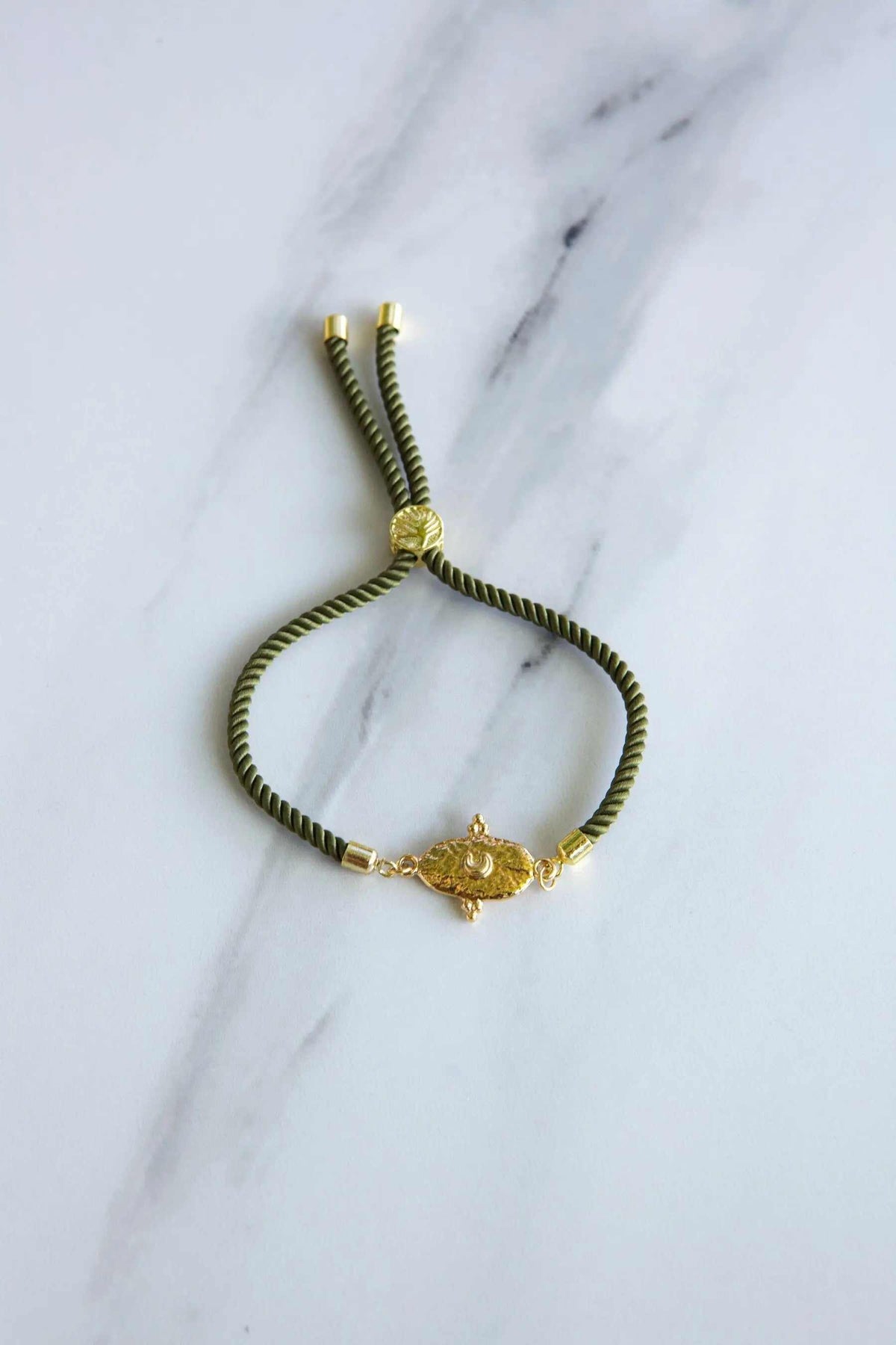 Adjustable rope Bracelet in olive green cord with gold-tone end caps, sliding knot and ornate central motif