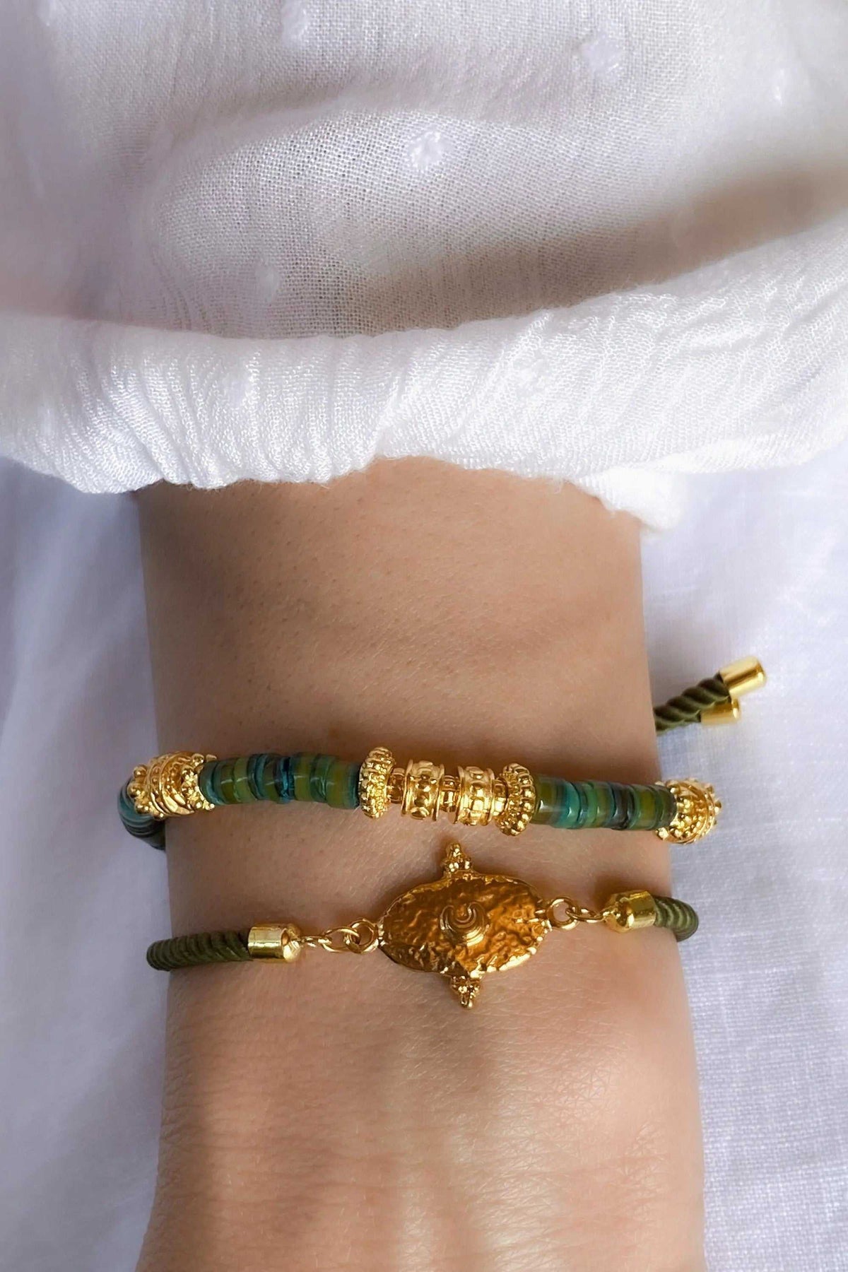 Adjustable rope Bracelet in olive green cord with ornate gold-tone tribal motif, gold spacers and adjustable ends