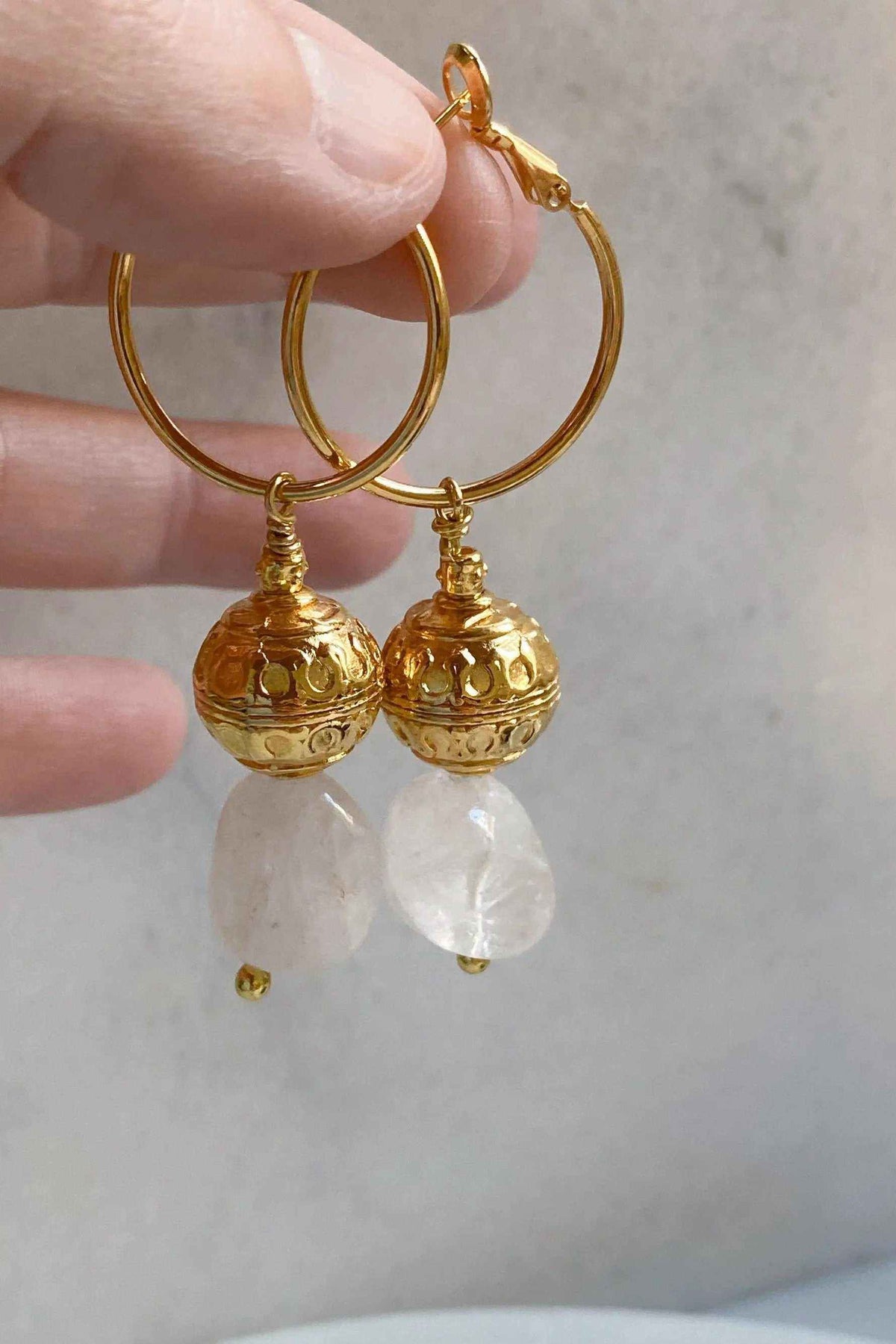 AGAPE EARRINGS with gold-tone hoops, ornate spherical charms, and translucent white quartz drop stones