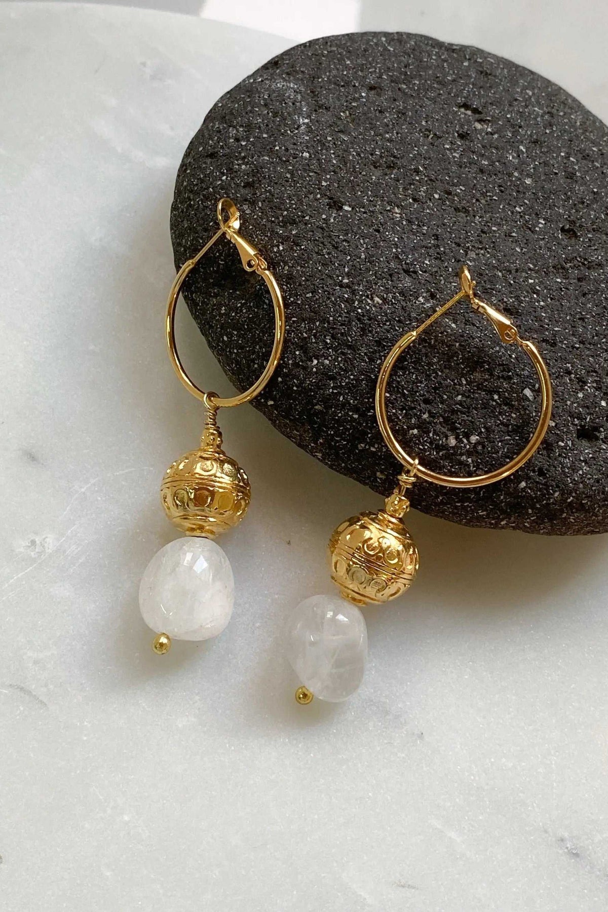 AGAPE EARRINGS feature gold-tone teardrop hoops, ornate spherical charms and dangling translucent white quartz stones.