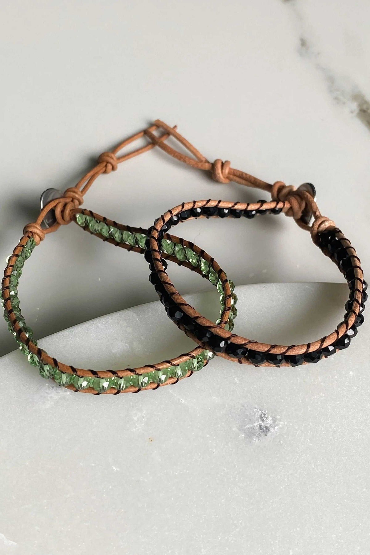 AGAPI BRACELET in brown leather with green and black crystal beads, featuring adjustable knotted cord closures