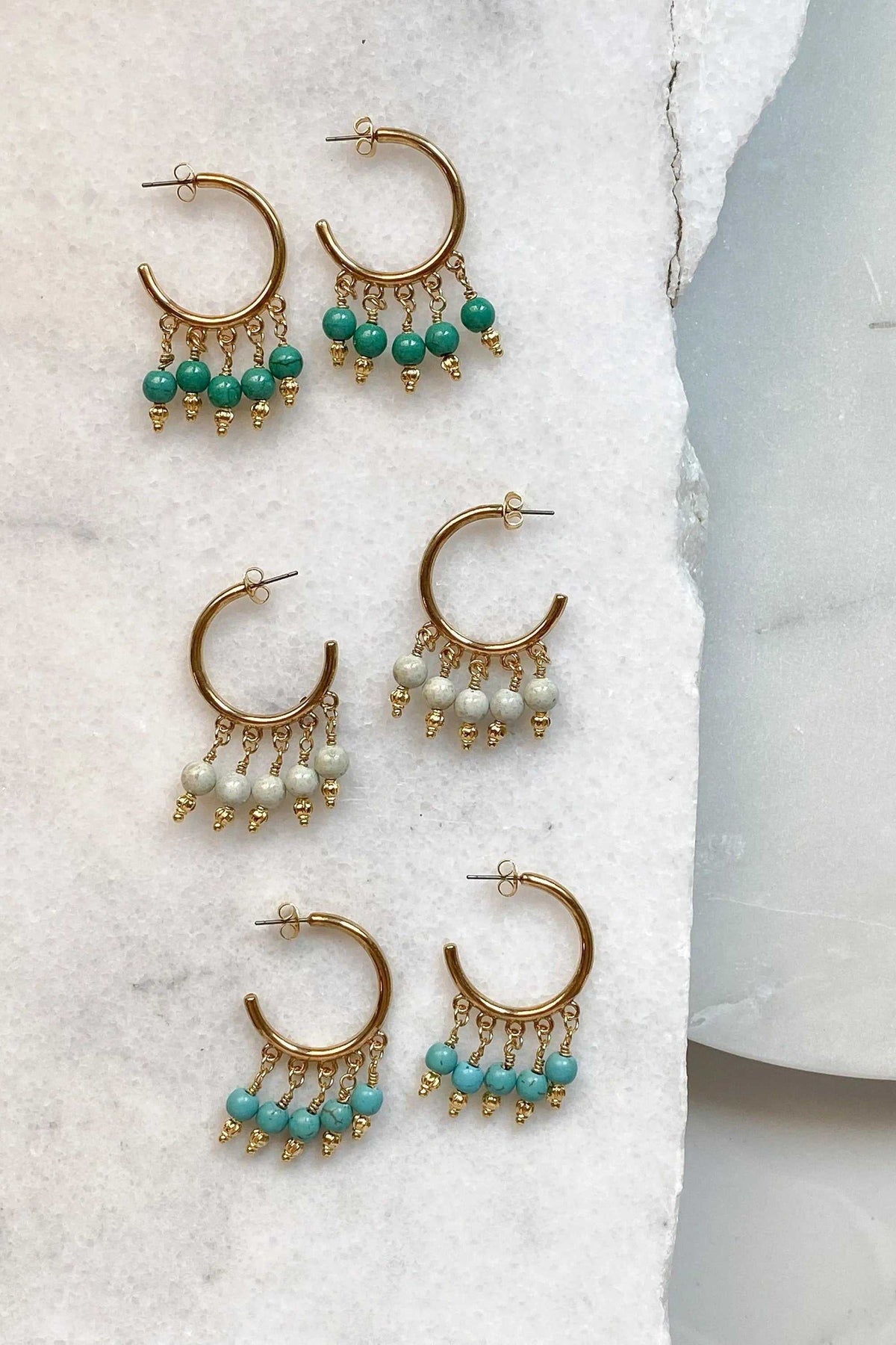 ALEX EARRINGS are gold-tone hoop earrings with dangling turquoise, green, and pale sage bead clusters and gold accents