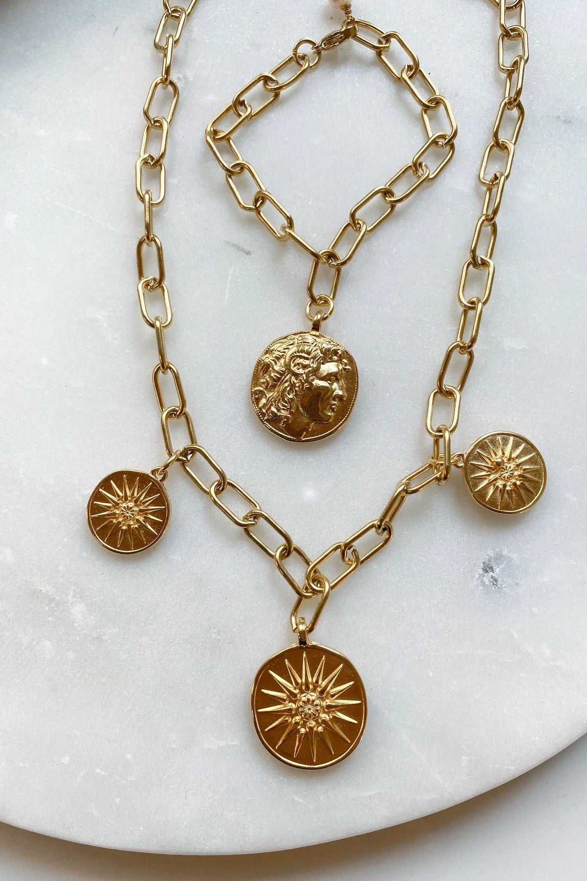 Alexander Charm Bracelet in gold-tone chunky link chain with round coin charms, including a raised portrait and starburst designs