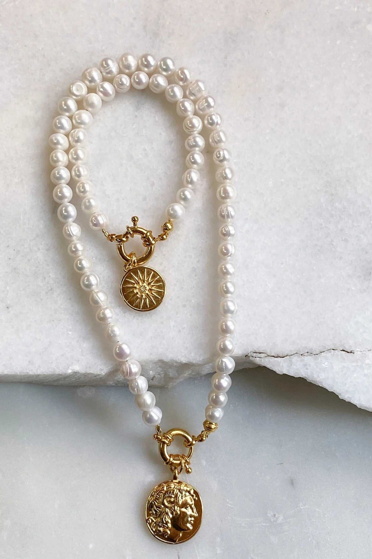 Pearl bracelet featuring lustrous white freshwater pearls, gold-tone links, a starburst charm and an Alexander the Great coin