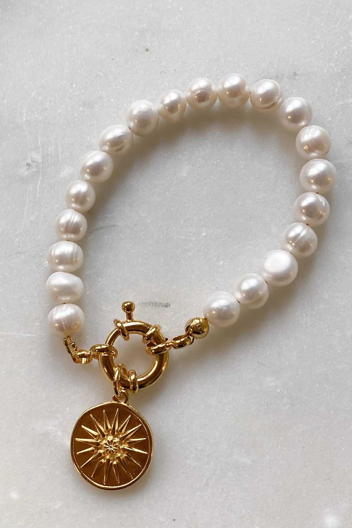 Pearl bracelet with creamy white freshwater pearls, a gold-tone clasp and medallion featuring the Alexander the Great star emblem