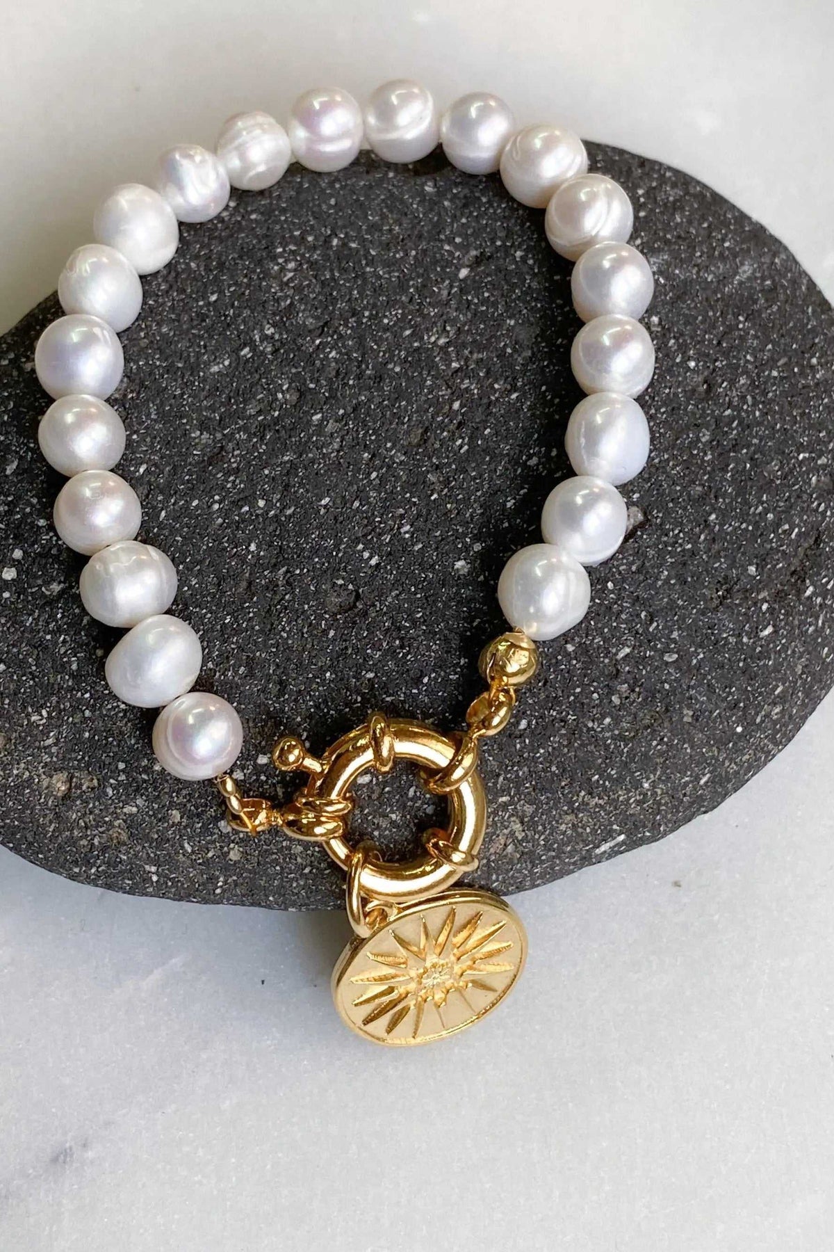 Alexander the Great pearl bracelet with lustrous white freshwater pearls and gold-tone clasp, finished with a sunburst coin charm.