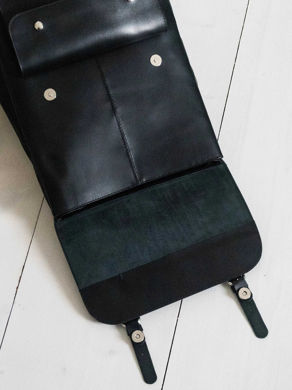 ALKION BACKPACK in black leather with a smooth flap, silver-tone snap fasteners, and a wide suede-textured panel