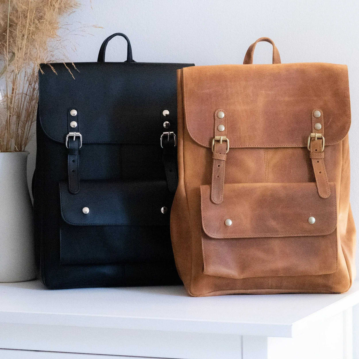 ALKION BACKPACK leather rucksack in black and tan, with front flap pockets, buckle straps, metal studs and top handles