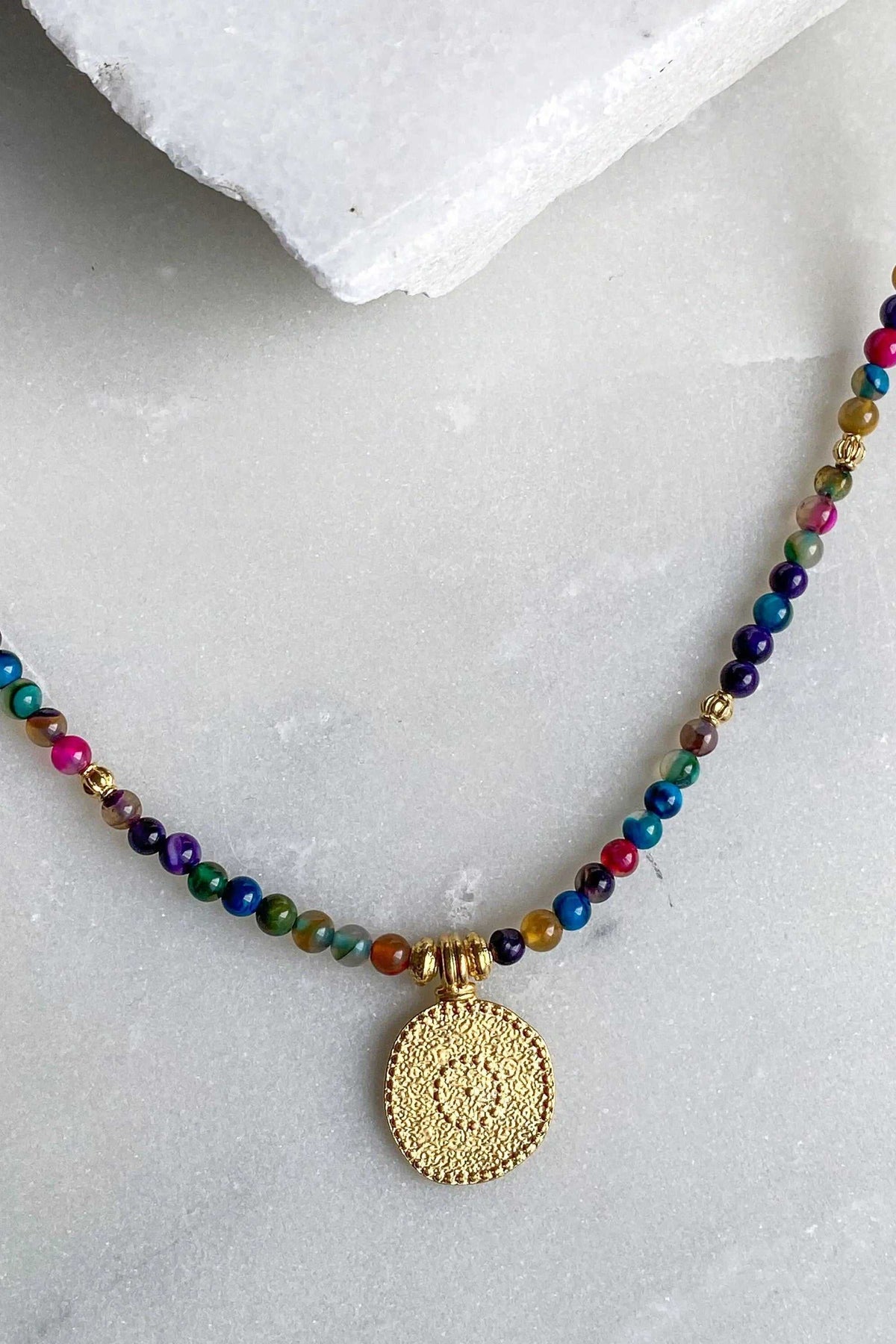 ALKYONI NECKLACE with multicoloured round beads and a textured gold-tone circular medallion pendant
