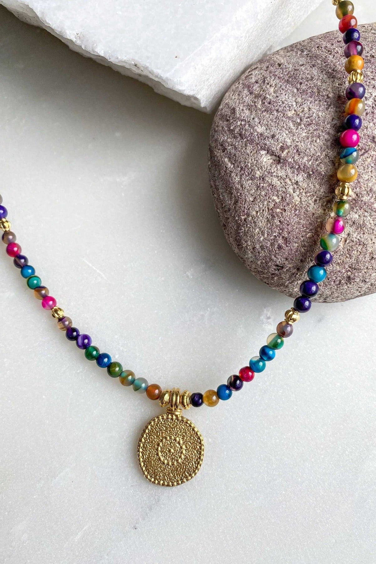 ALKYONI NECKLACE with a strand of multicoloured polished beads and a round textured gold-tone medallion pendant