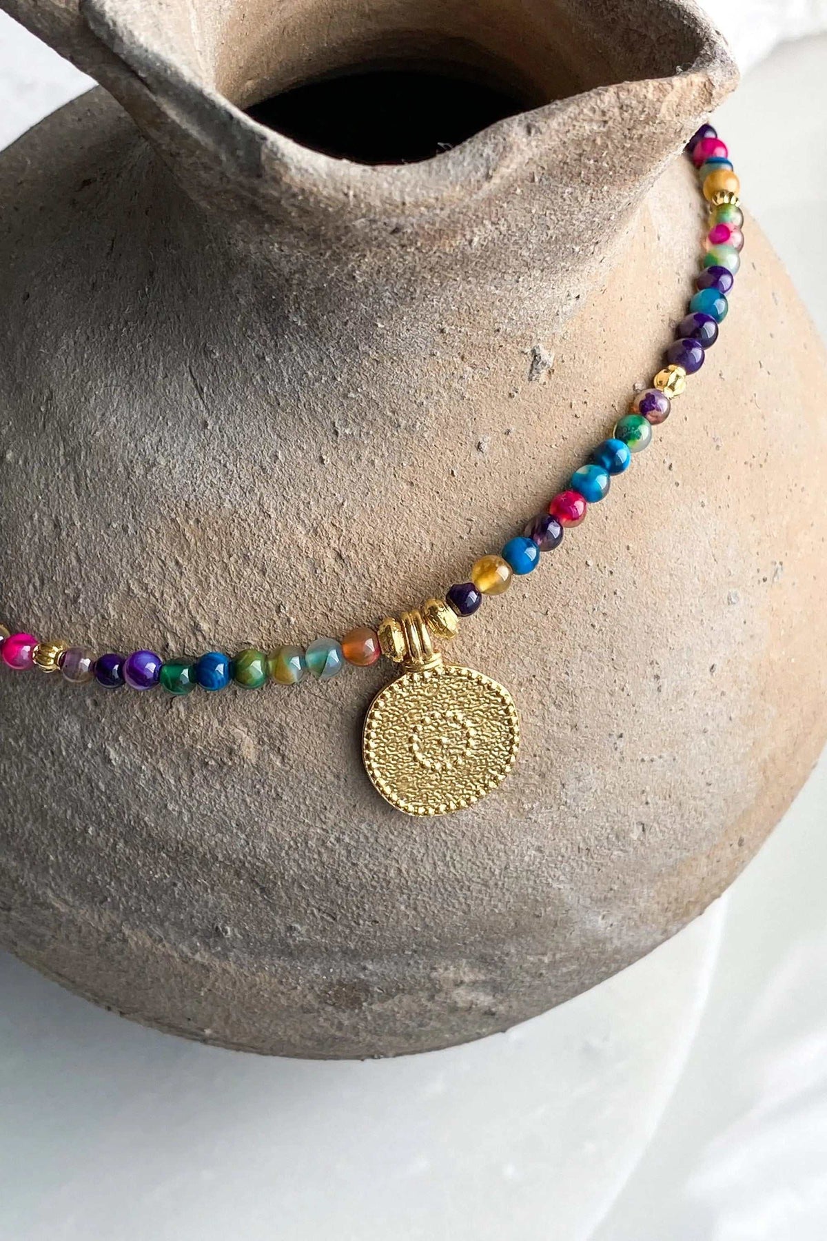 ALKYONI NECKLACE with multicoloured polished gemstone beads and a round textured gold-tone pendant