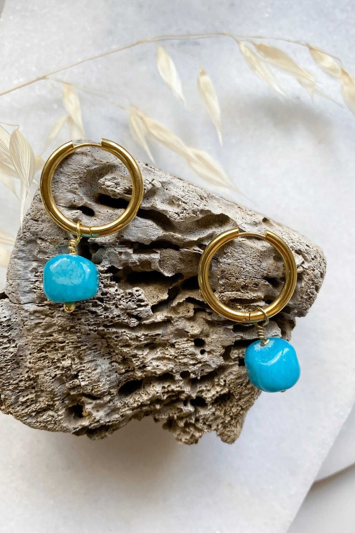 Large hoop earrings in gold-tone metal with bright turquoise stone charms and smooth circular hoops