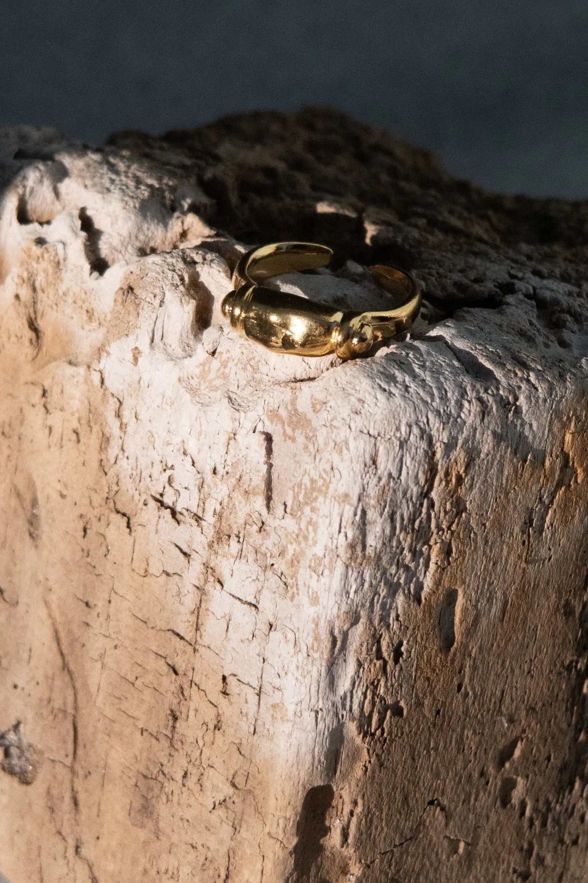 Ancient Greek ring in polished gold-tone metal, featuring a sculpted rounded centerpiece and an adjustable open band