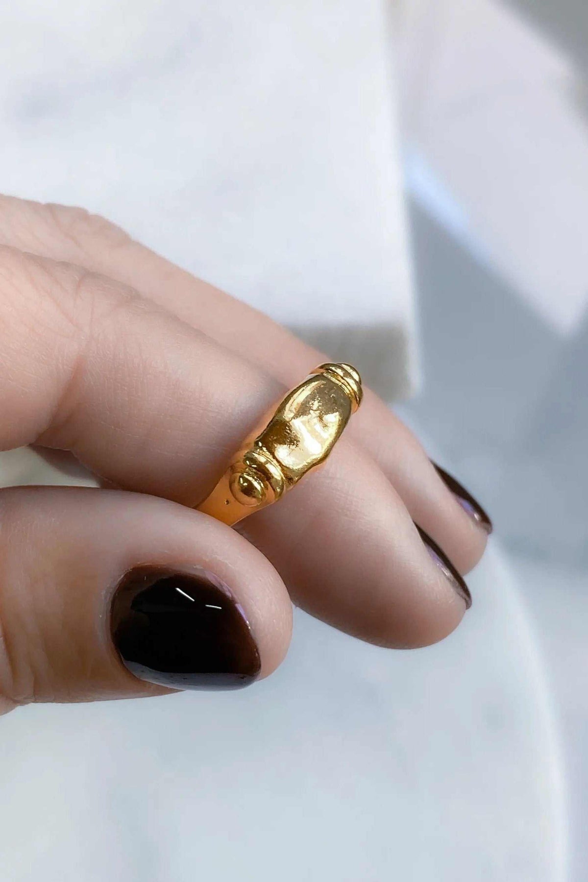 Ancient Greek ring in shiny gold-tone metal, featuring a raised sculpted face and decorative details on a broad band