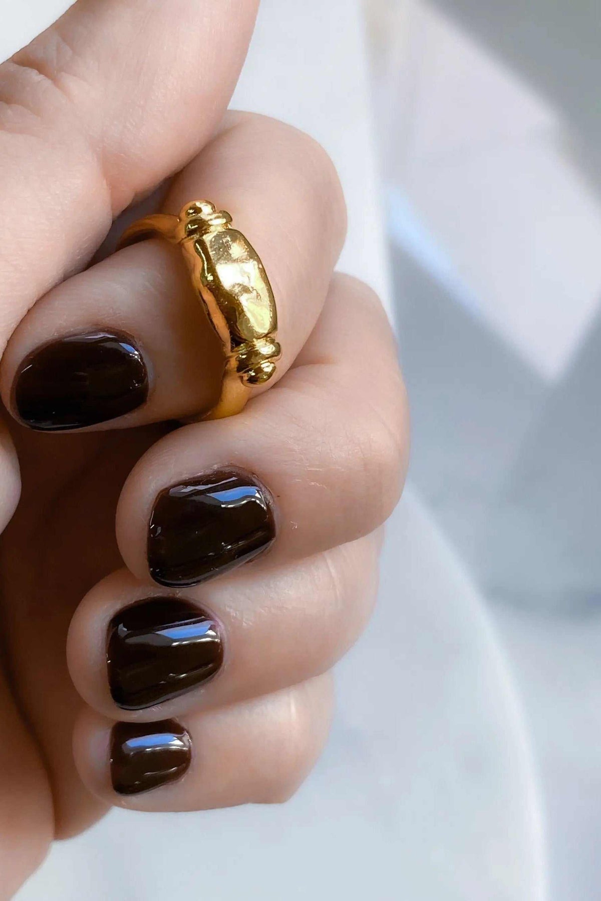 Ancient Greek ring in shiny gold tone with a raised, sculptural oval centerpiece and rounded decorative ends