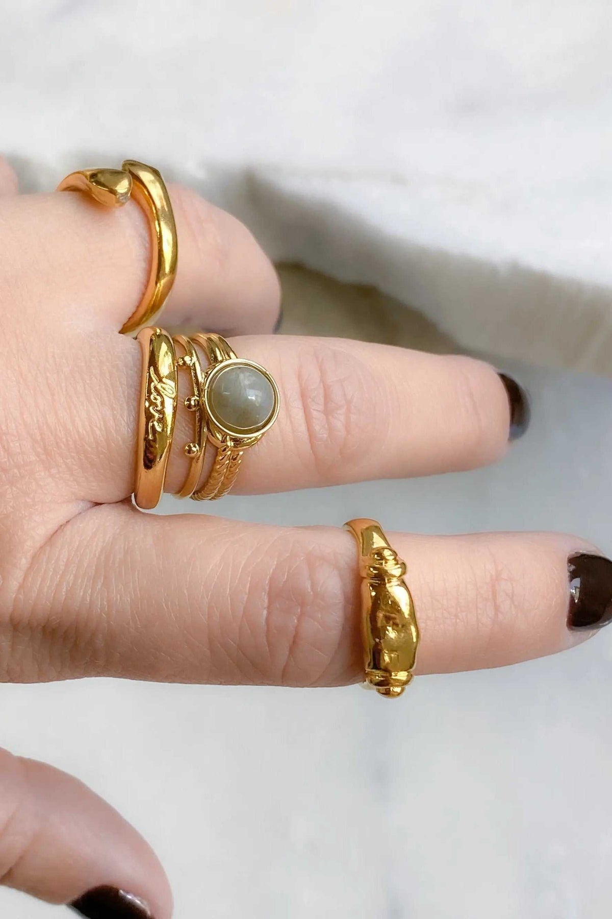 Ancient Greek ring set in gold-tone metal, featuring ornate textured bands and a round pale grey stone accent