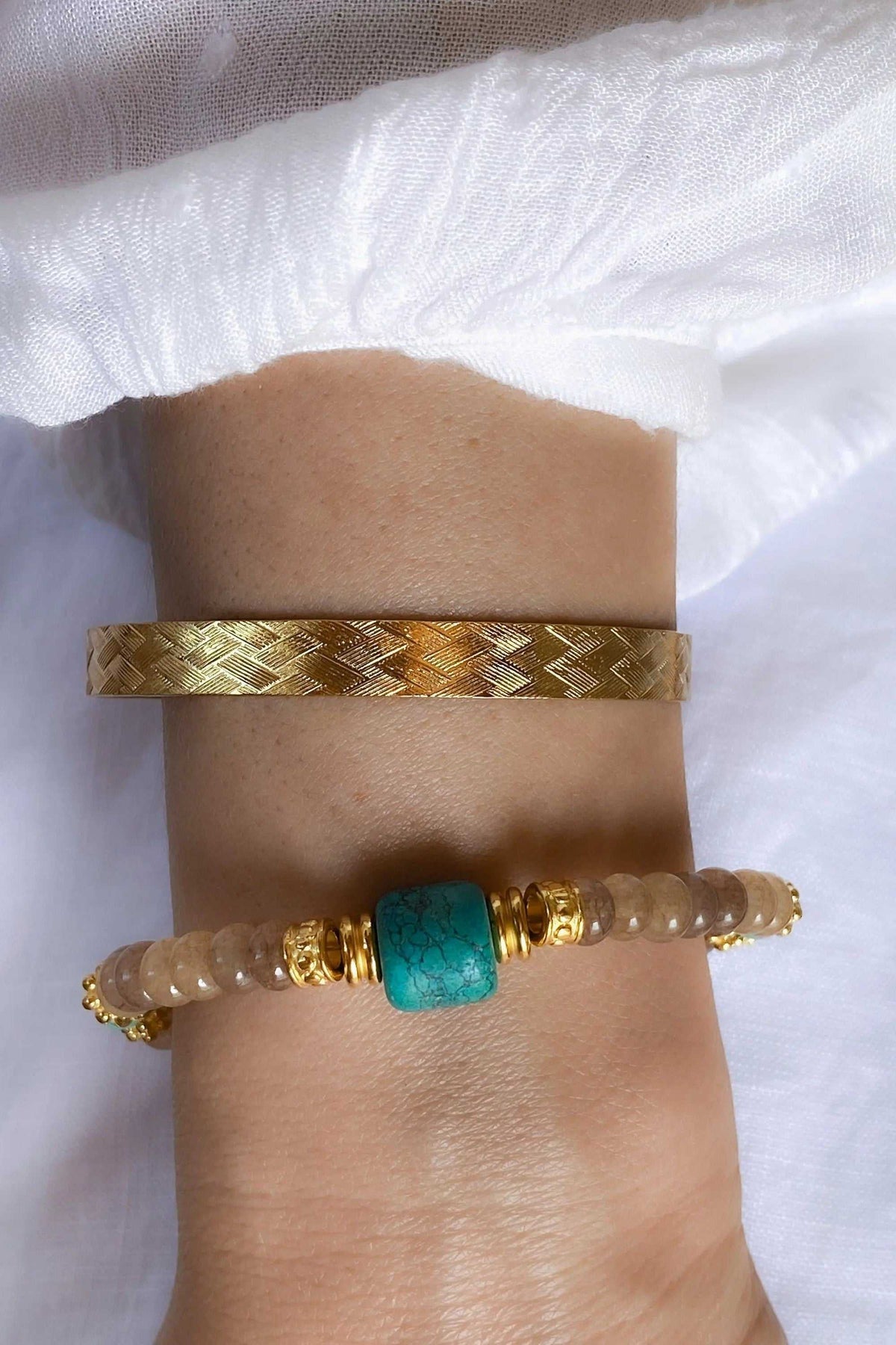 ARETI Bracelet with translucent brown agate beads, a turquoise stone and gold-tone accents, worn beside a woven gold-tone cuff
