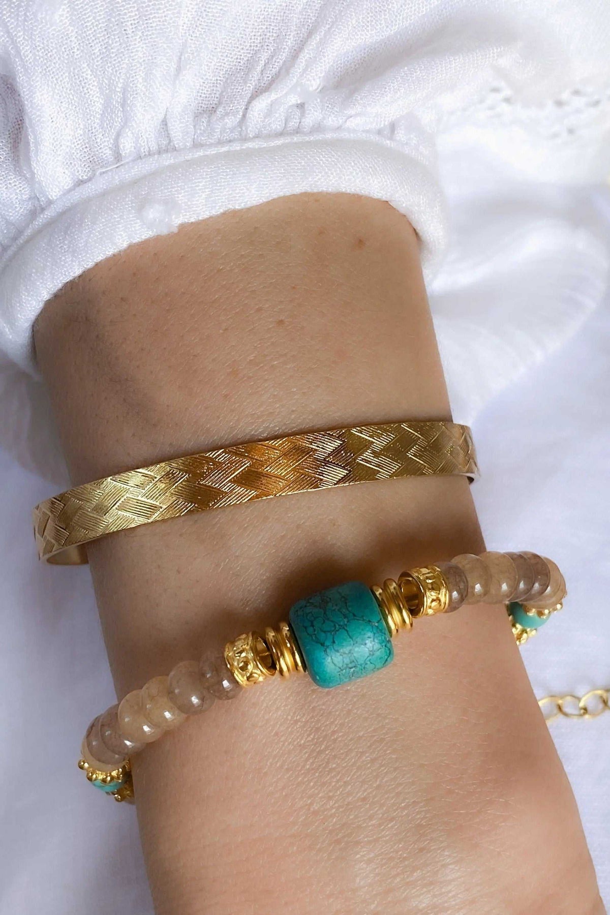 ARETI Bracelet with pale translucent agate beads, a prominent turquoise stone and ornate gold-tone details beside a woven gold-tone cuff