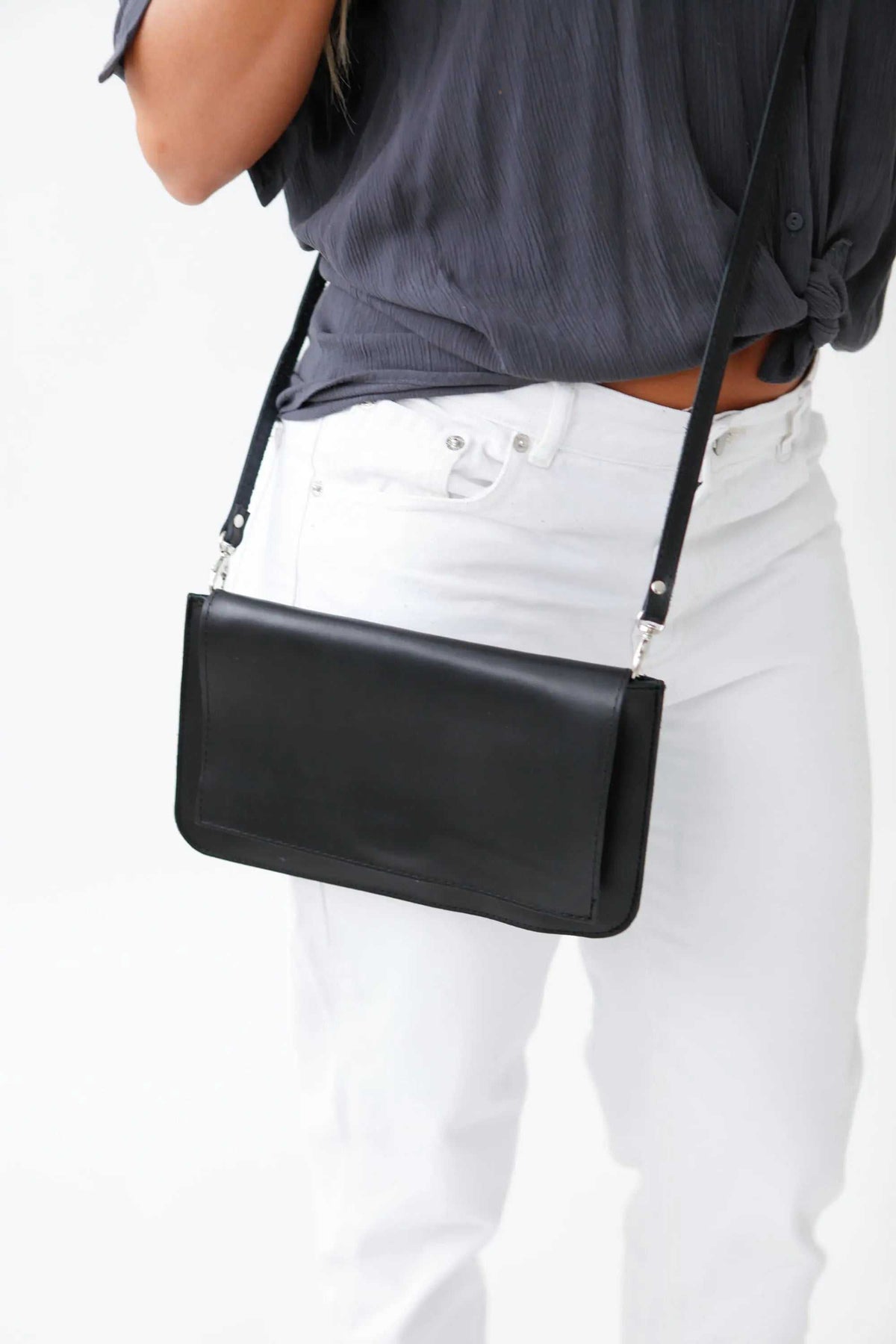 ARION black leather envelope bag with a smooth finish, large front flap, and slim adjustable shoulder strap