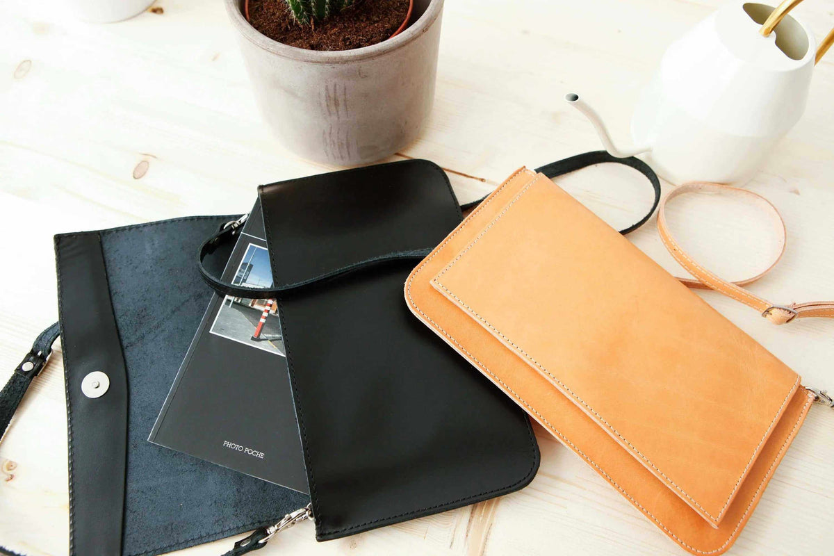 ARION envelope bag in black and tan leather, with stitched edges, flap closures, and detachable shoulder straps