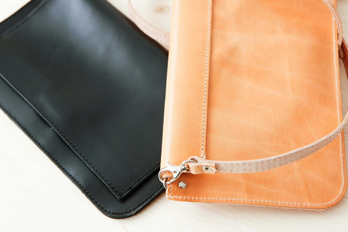 ARION leather envelope bag in black and natural tan, with smooth surfaces, stitched edges and removable straps