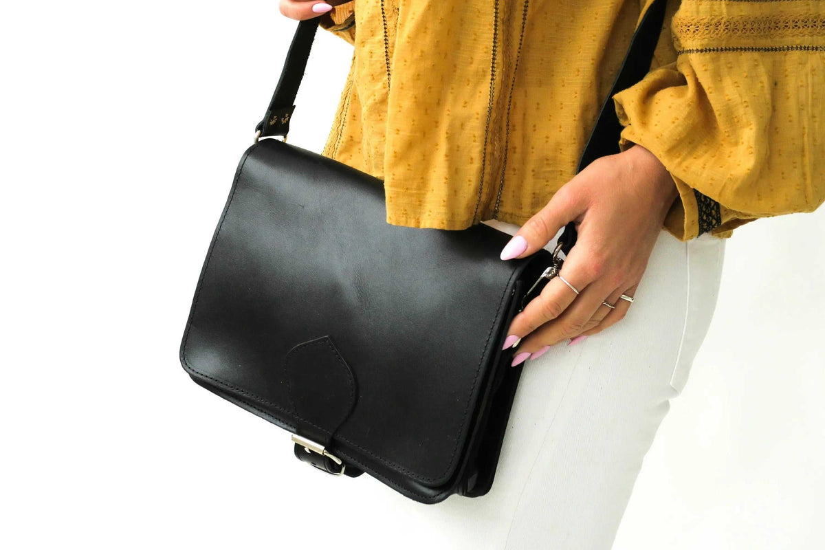 ATHINAÏS shoulder bag in smooth black leather with a structured flap, adjustable strap and metallic buckle