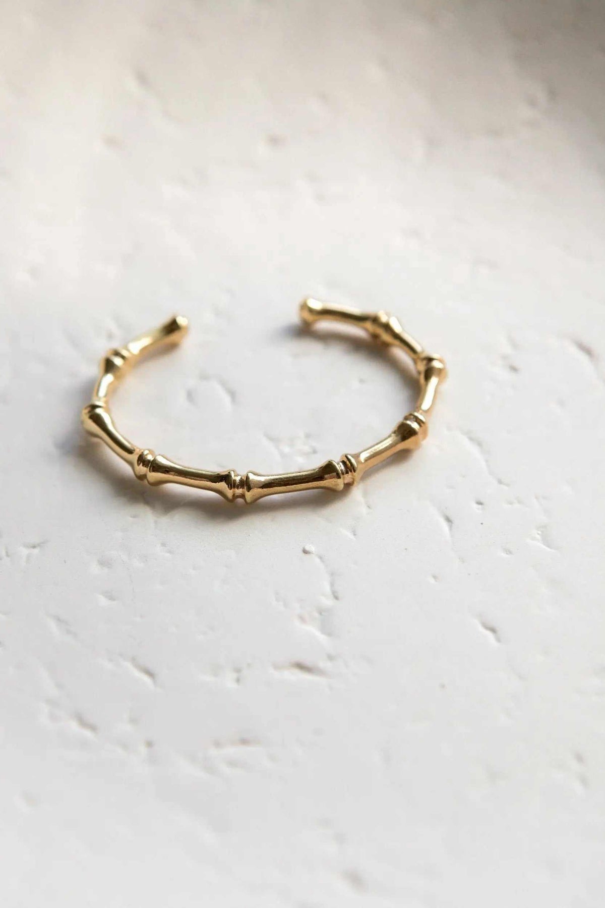 Bamboo pattern bracelet in gold-tone metal, formed from slender segmented bamboo-like links with a delicate open cuff design