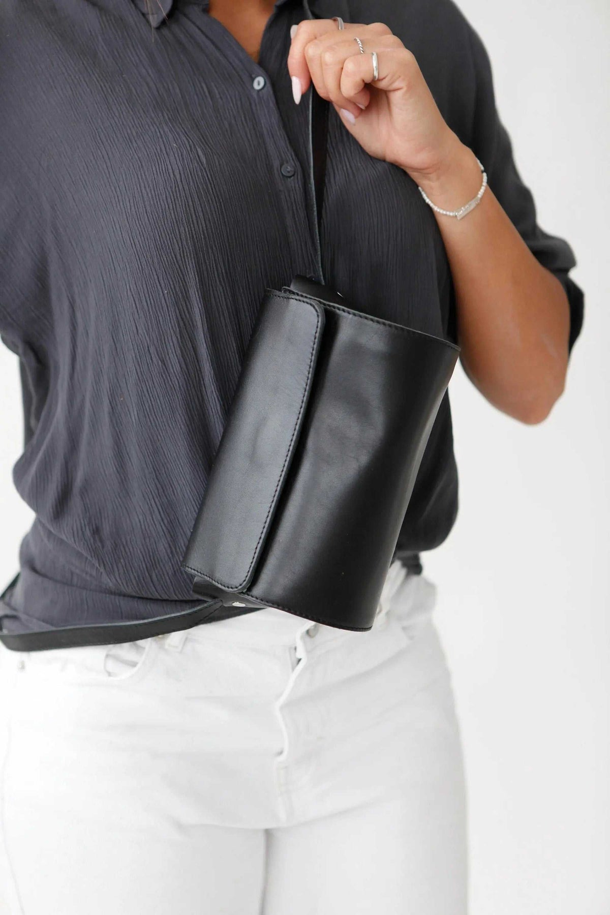 Barrel Bag in smooth black leather with a cylindrical shape, broad adjustable shoulder strap and clean stitched panels