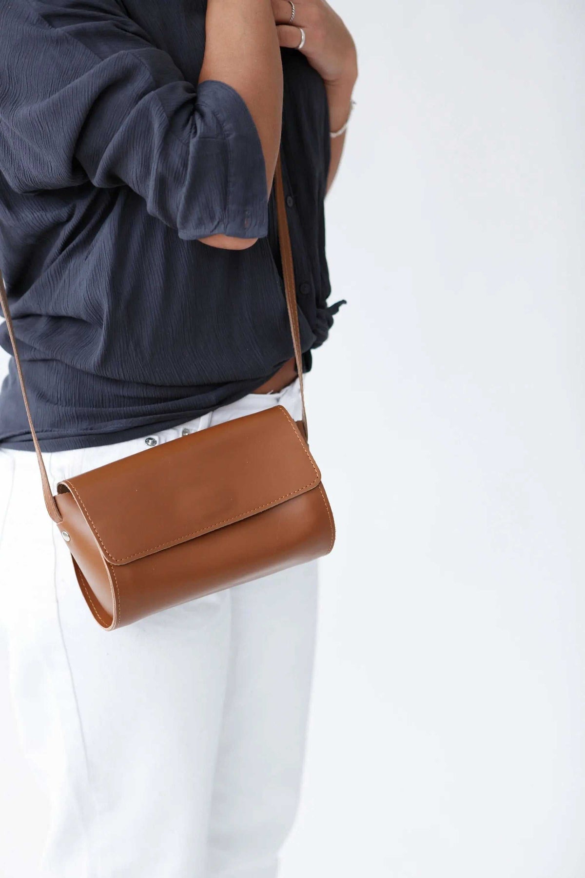 Barrel Bag in smooth camel-brown leather with a structured cylindrical shape, flap closure and slim shoulder strap