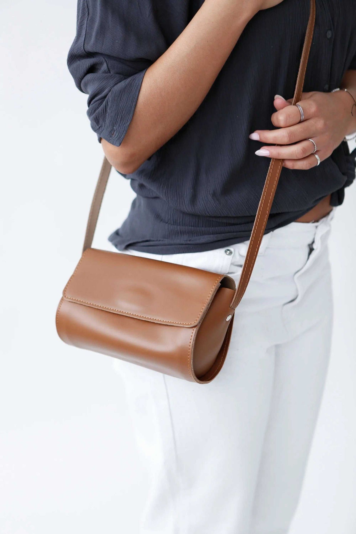 Barrel Bag in smooth camel-brown leather with a rounded cylindrical body, stitched flap and long adjustable strap