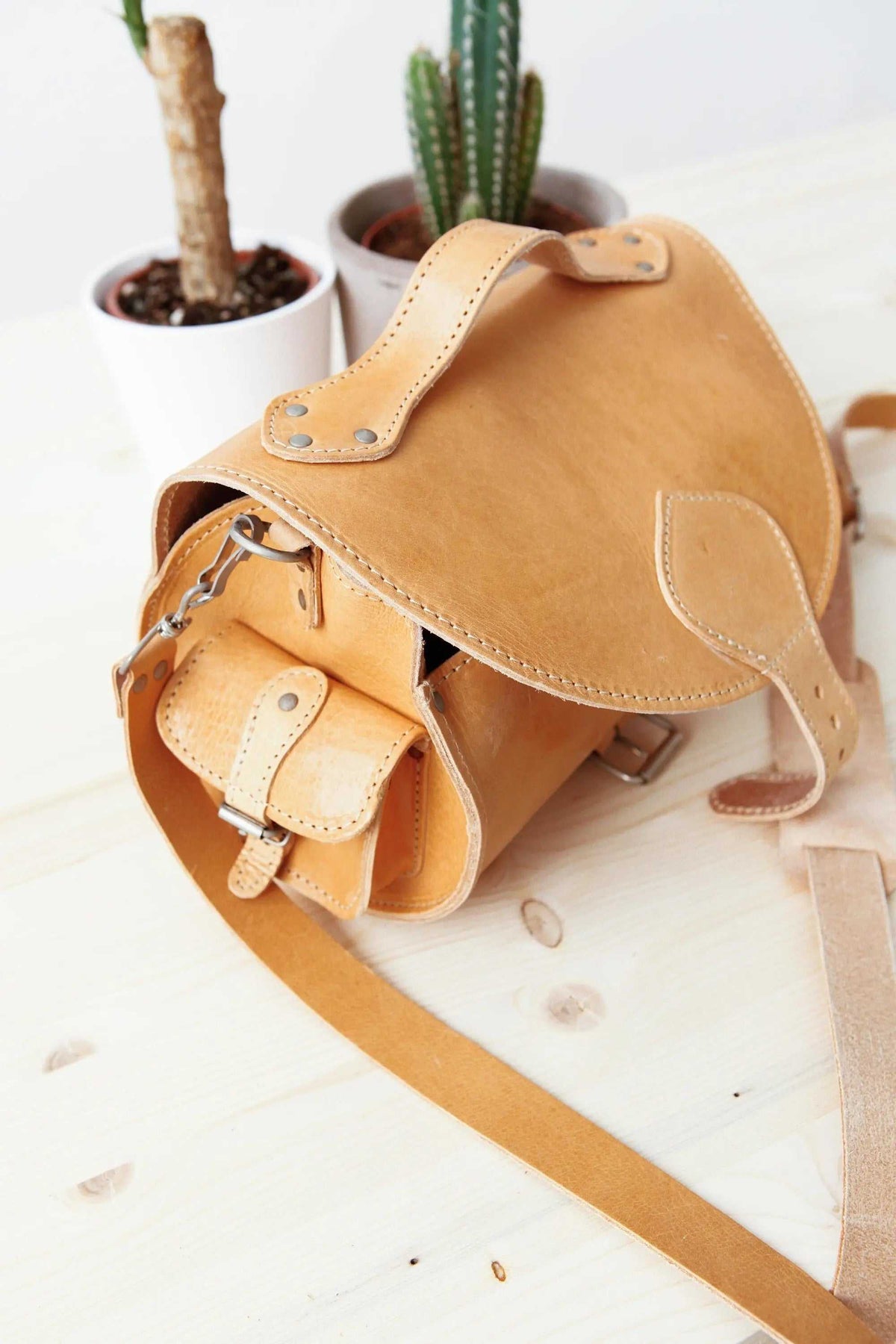 BARREL BAG with pockets in natural tan leather, featuring a rounded shape, flap closure, metal buckles and adjustable strap