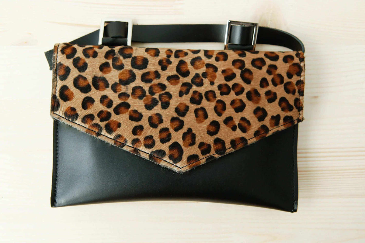 belt bag in black leather with a brown leopard-print flap, rectangular shape, and two metallic buckle details