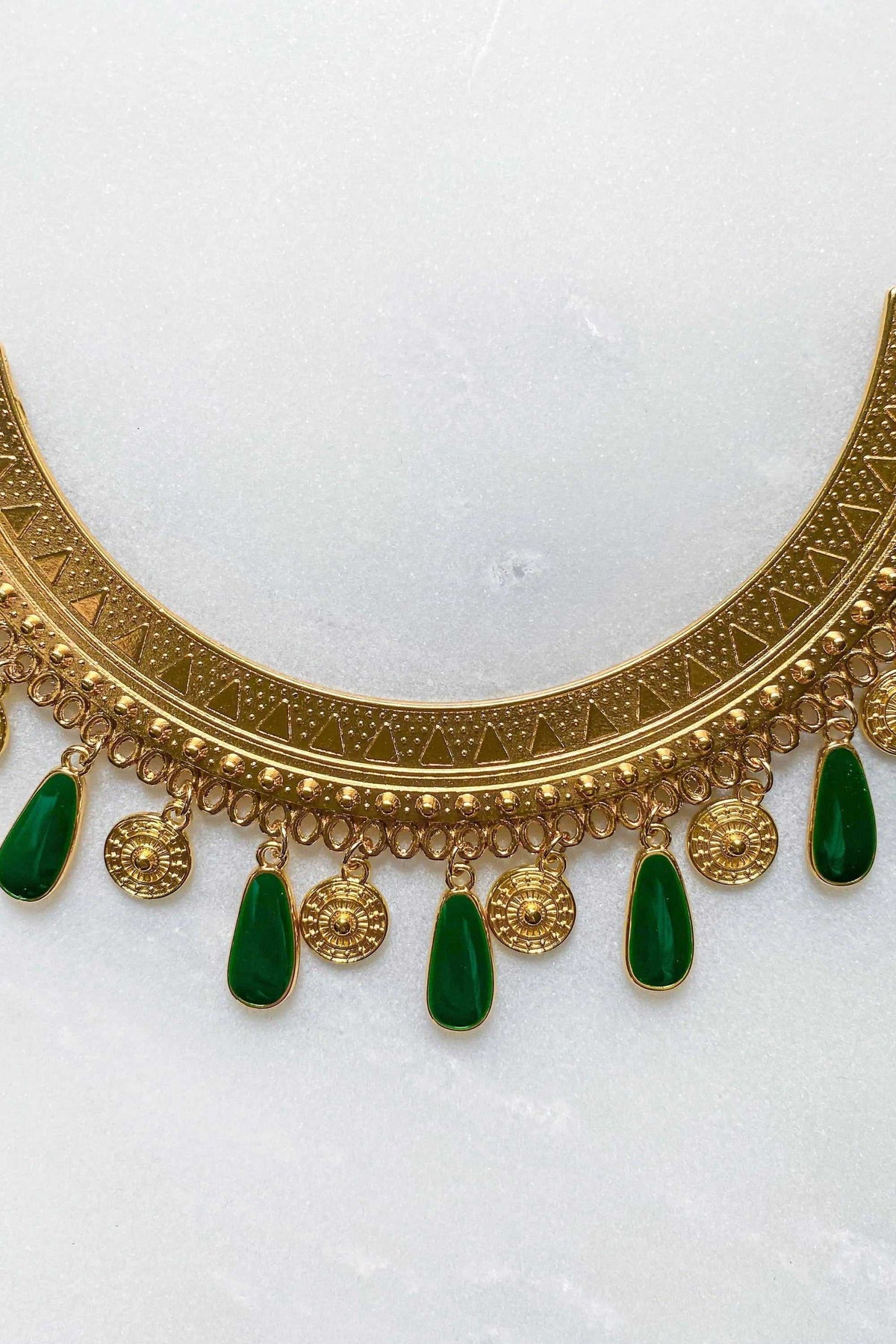Boho chic necklace with a broad gold-tone etched band, round coin charms and dangling deep green enamel drops