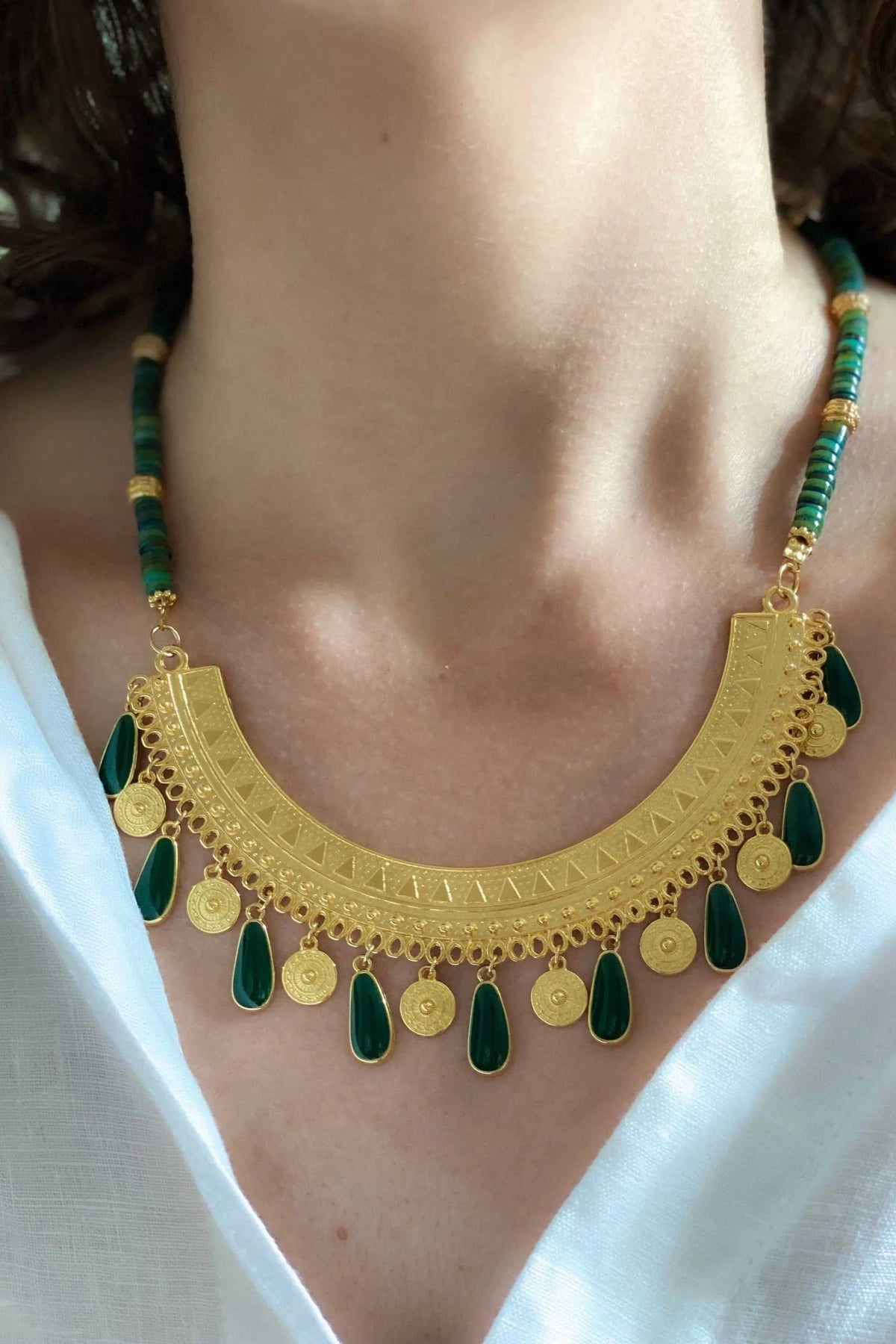 Boho chic necklace with gold-tone filigree pendant, green beads, and dangling teardrop and coin charms